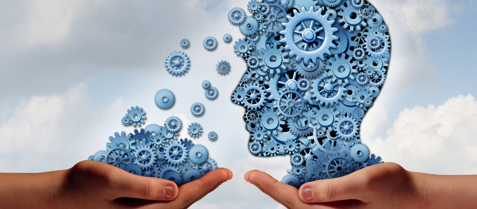 Training and development business education concept with a hand holding a group of gears transfering the wheels of knowledge to a human head made of cogs as a symbol of acquiring the tools for career learning.